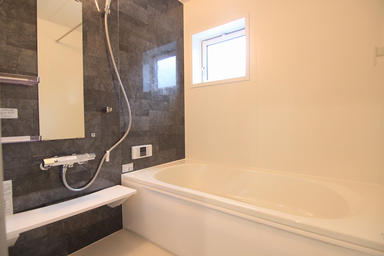 【浴室/1号棟】　落ち着いたカラーのパネルを採用した浴室は、自然換気ができる小窓付き。雨の日や夜間でも洗濯物を乾かせる、浴室乾燥機を設置しています。