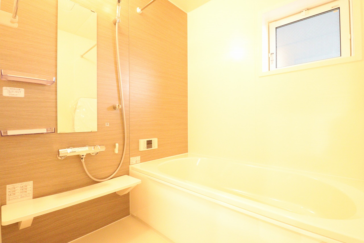 【2号棟浴室】　落ち着いた色合いのアクセントパネルを施したゆとりのある浴室です。雨の日や夜間の洗濯物干しを可能にする、便利な浴室乾燥機が付いています。